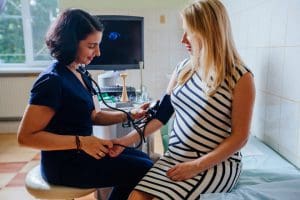 NP taking pregnant woman's blood pressure