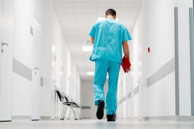 A nurse walking alone down a hallway