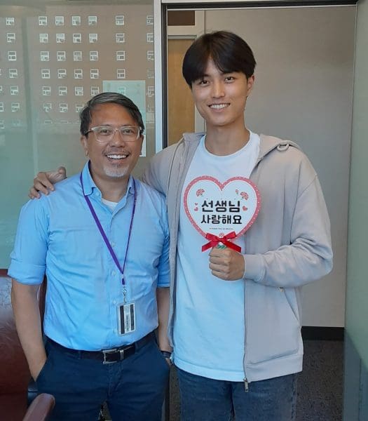 Professor Lim with his student, Sam Lee, holding a sign that says "thank you teacher" in Korean